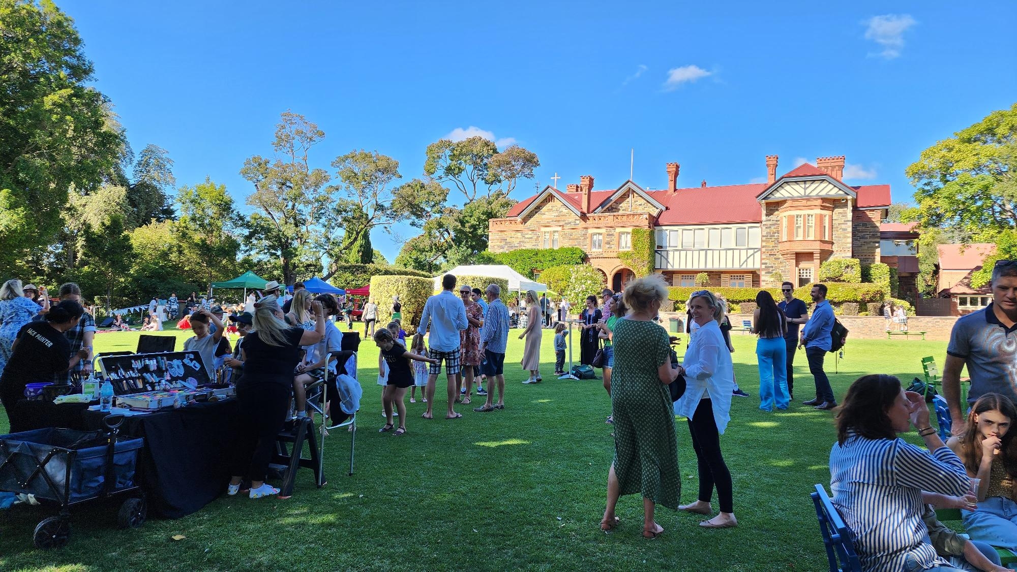 Families and students gathered on the lawns in front of the historic Mercedes College building during a community event.