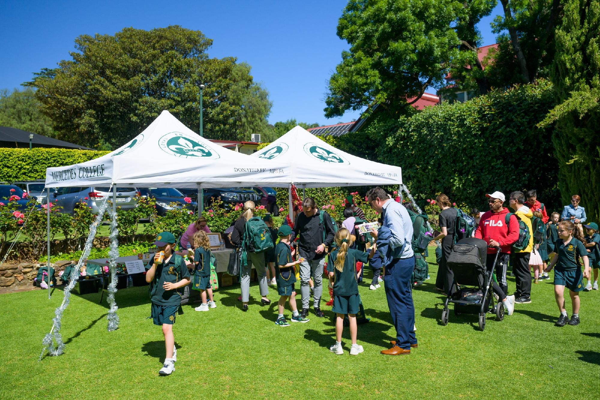 Crowds of students, parents and educators enjoying activities on the Mercedes College lawns with marquees and displays set up.