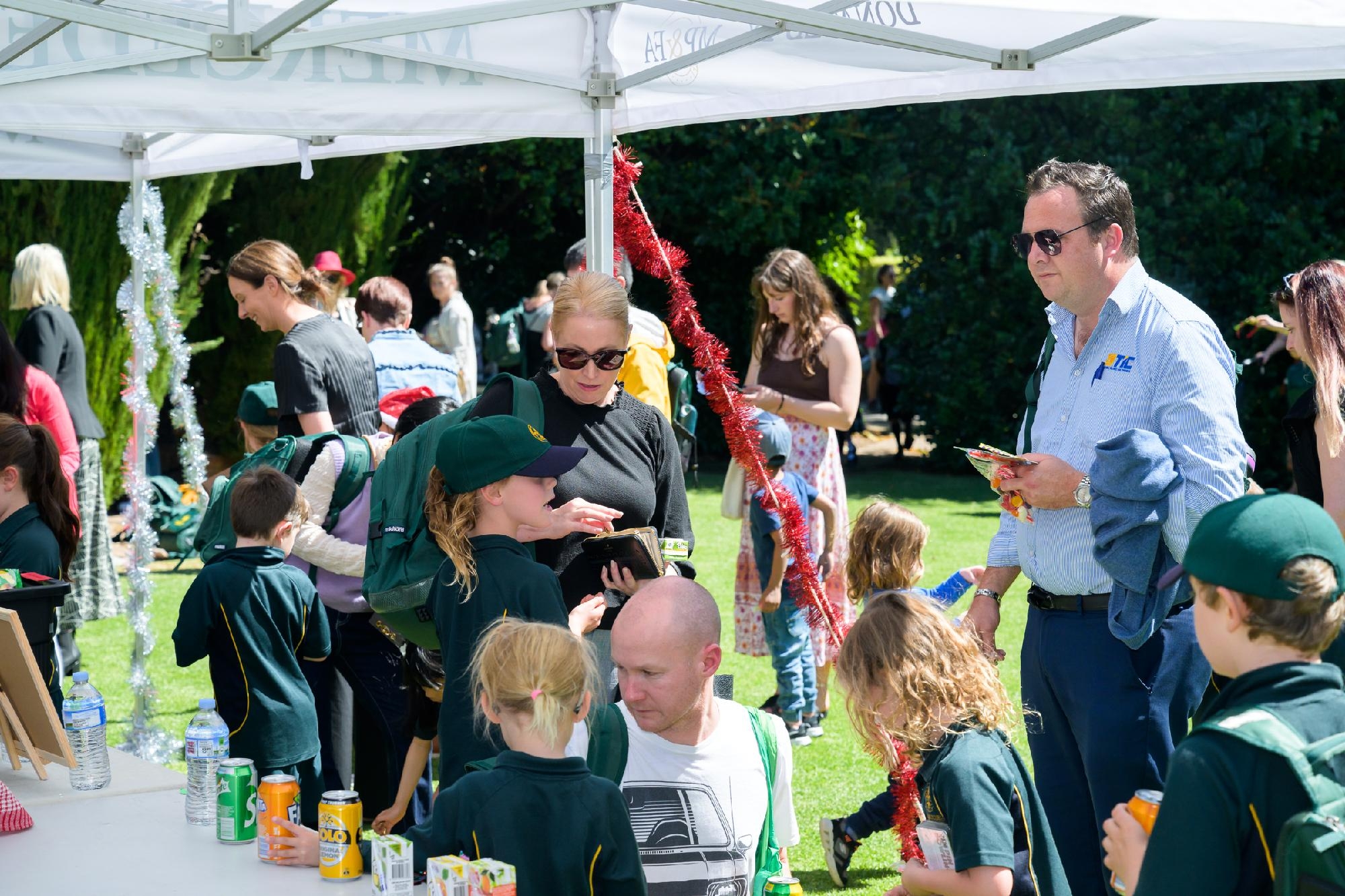Parents and children gathered under a marquee at a Mercedes College community event.