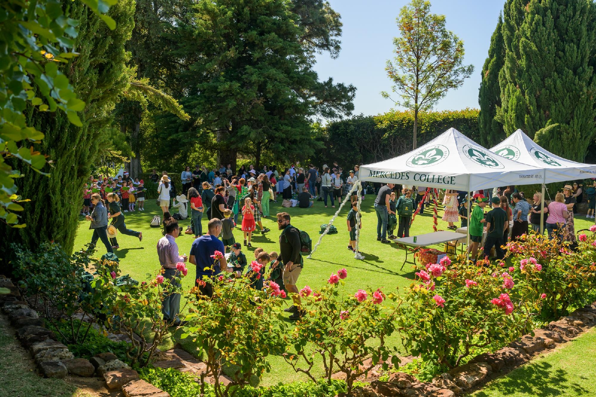 Families and students gathered on the lawns at Mercedes College under marquees during a school fair.