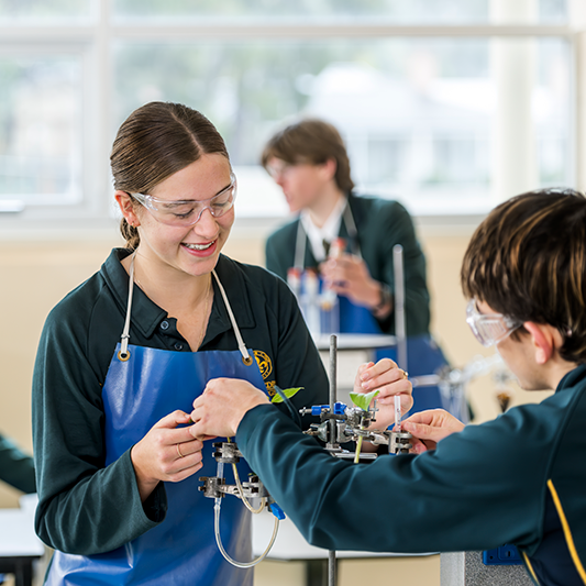 Senior School students at Mercedes College conducting a science experiment with lab equipment and safety gear in a modern classroom.