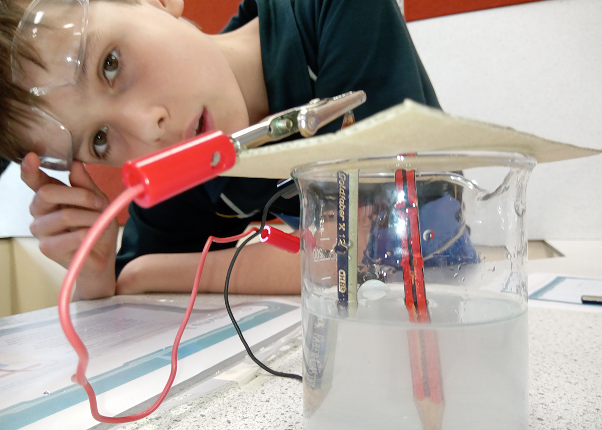 Close-up of a Mercedes College student observing a classroom science experiment involving electricity and water.